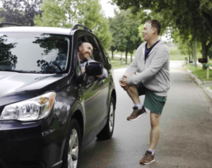 Image of a jogger stopped to talk to a driver in his vehicle.