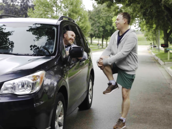 Image of a jogger stopped to talk to a driver in his vehicle.