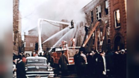 Scene from WTTW's Chicago Stories: Angels Too Soon. A fire breaks out a school on the West side of Chicago. Firefighters work to bring the fire down and civilians watch on the sidewalk.